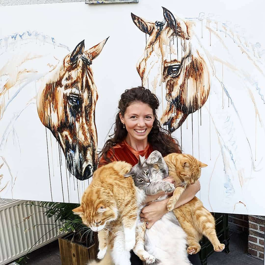 Marjo Lebbe with her cats in front of a horse painting
