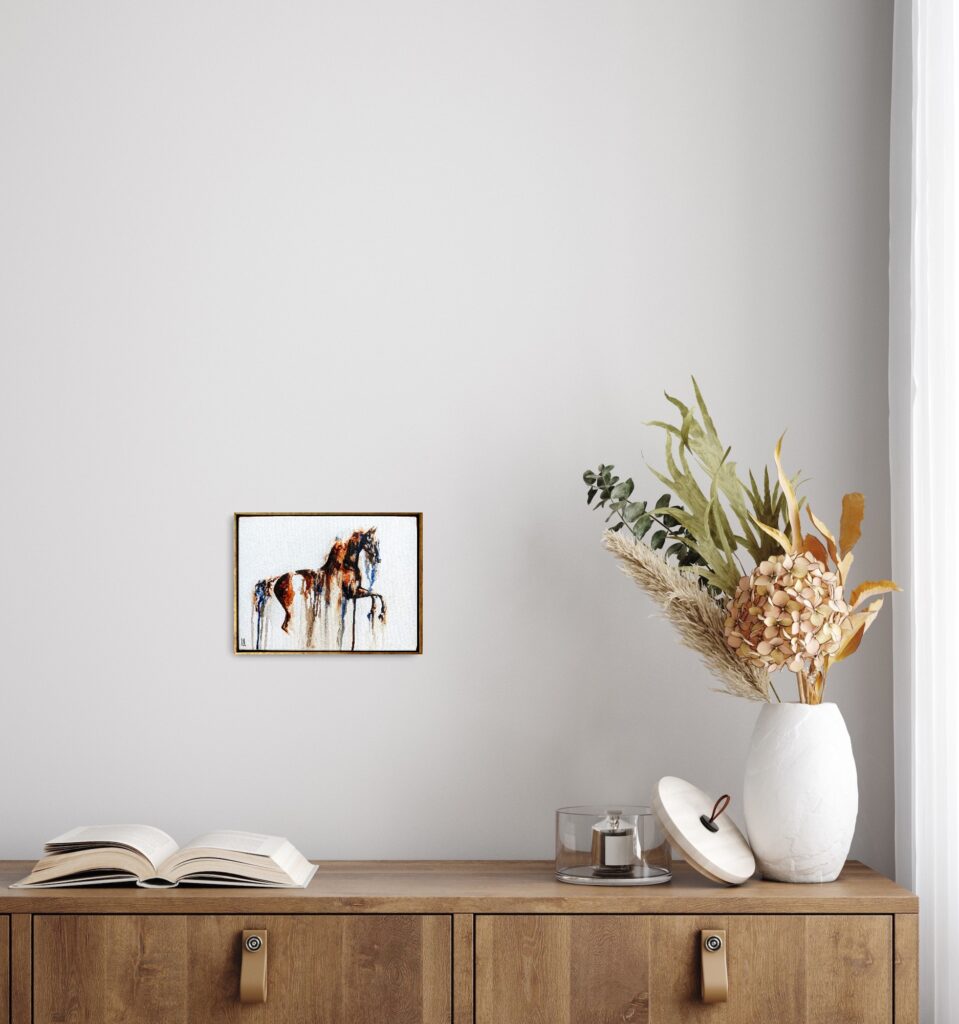 A framed horse artwork above a cabinet